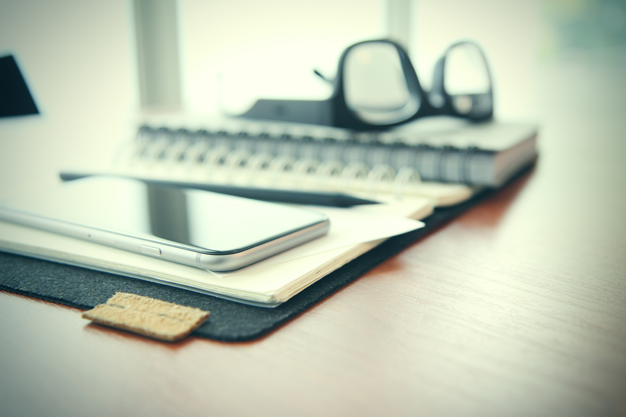 Smart phone close-up, planning book on wooden desk work space concept